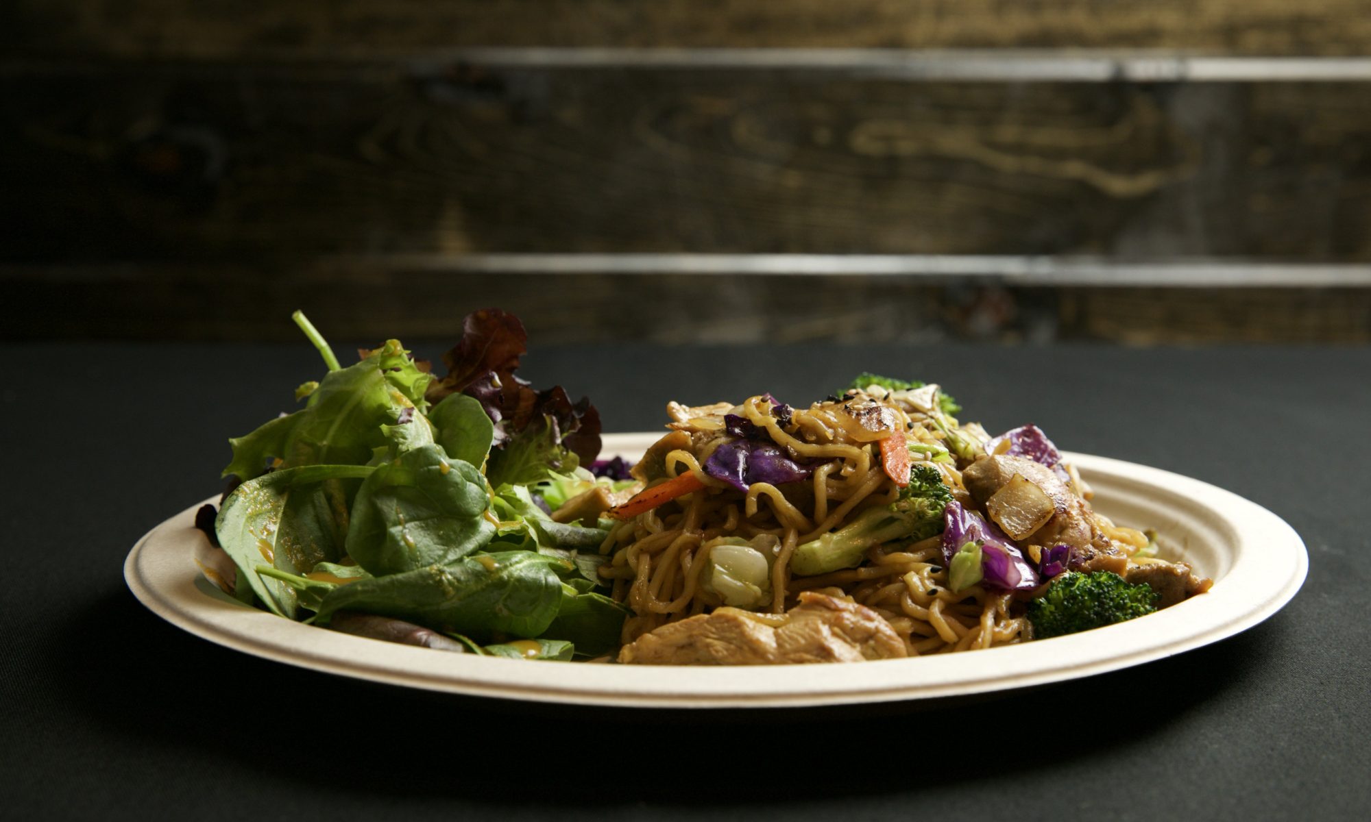 plate of noodles with chicken and vegetables and greens